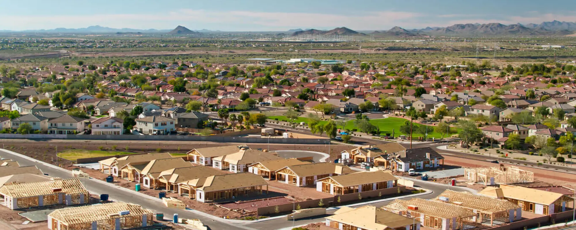 Aerial view of Peoria, Arizona residential neighborhoods with new home construction and distant mountain ranges