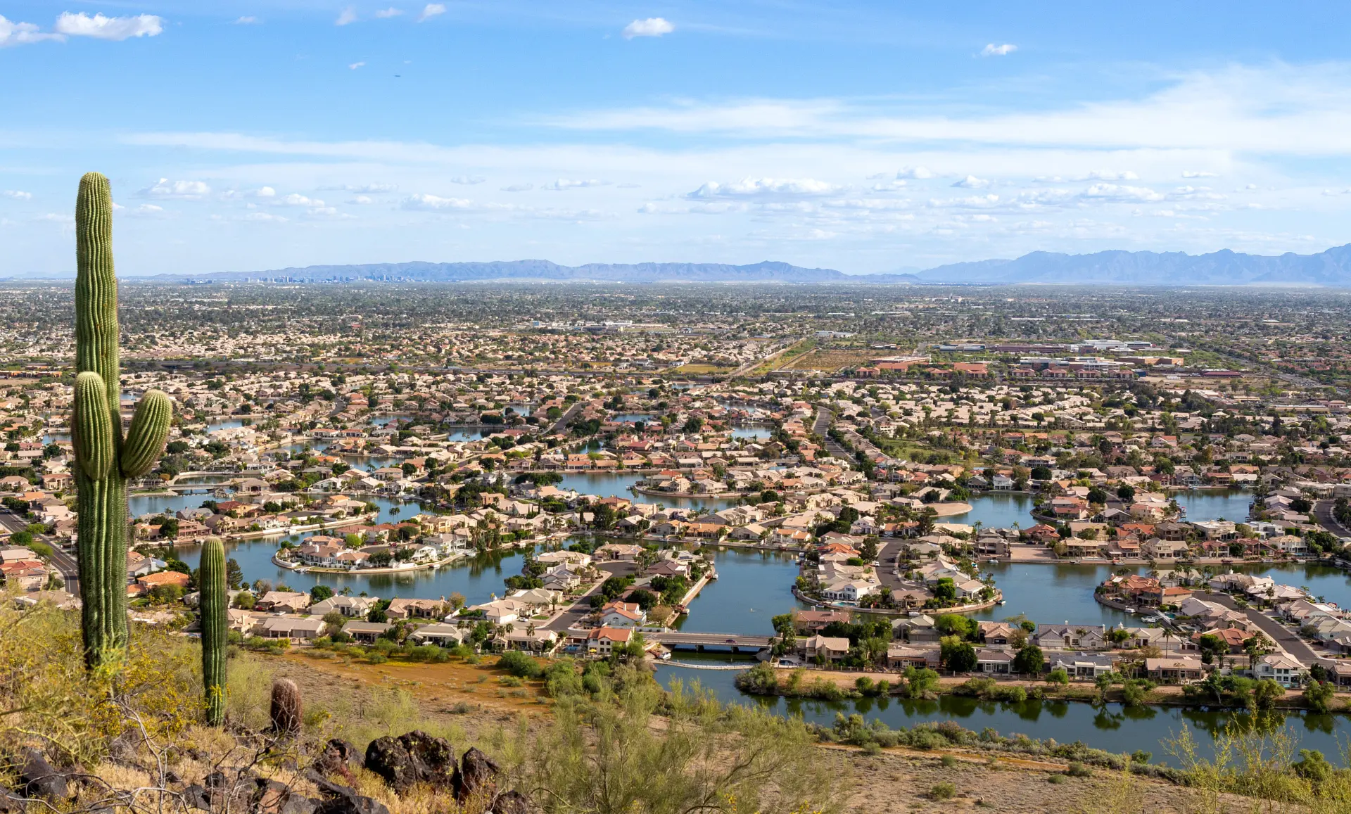 Aerial view of Glendale, Arizona with lakefront homes, saguaro cacti and mountain backdrop